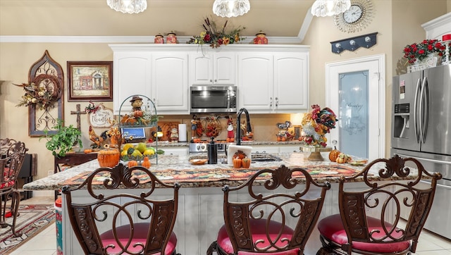 kitchen with a kitchen island, crown molding, white cabinetry, light tile patterned floors, and appliances with stainless steel finishes