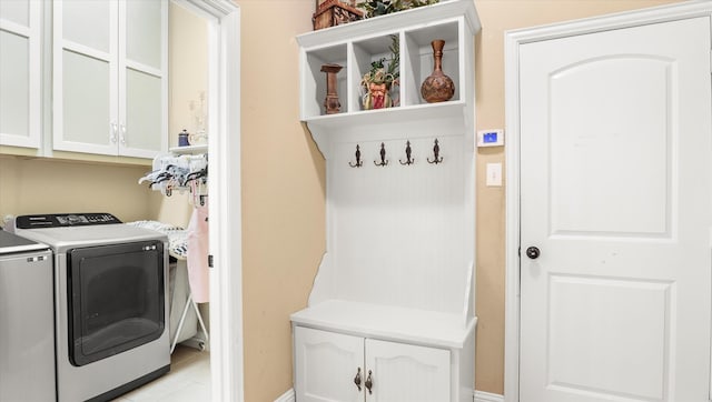 laundry room featuring washer and clothes dryer, light tile patterned floors, and cabinets