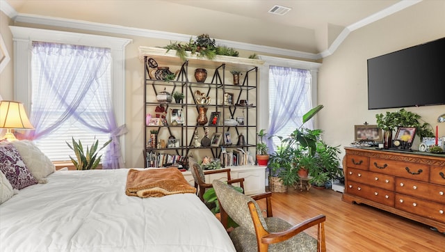 bedroom featuring light hardwood / wood-style floors, multiple windows, and ornamental molding