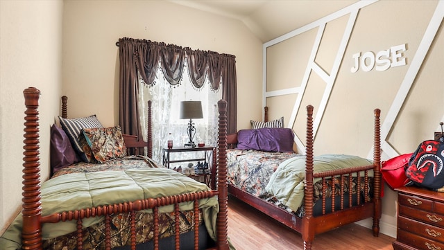 bedroom with lofted ceiling, hardwood / wood-style floors, and multiple windows