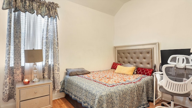 bedroom with lofted ceiling and wood-type flooring