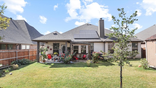 back of property featuring a patio, a yard, and solar panels