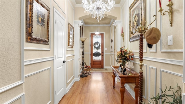 doorway to outside with a notable chandelier, ornamental molding, and light wood-type flooring