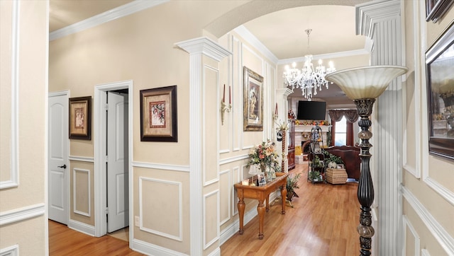 hall with crown molding, hardwood / wood-style floors, and ornate columns