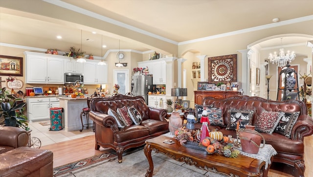 living room with an inviting chandelier, light hardwood / wood-style flooring, ornamental molding, and ornate columns