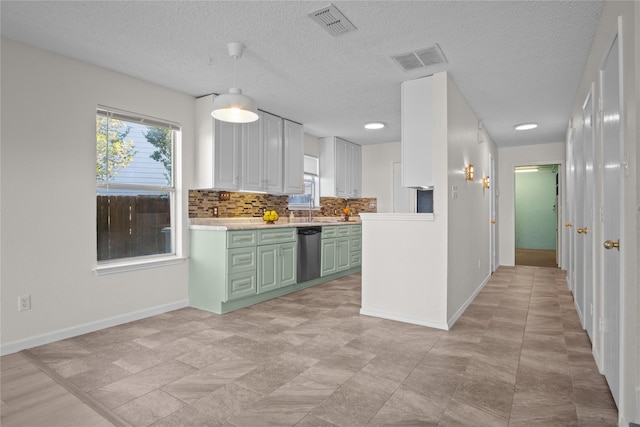 kitchen with backsplash, a textured ceiling, stainless steel dishwasher, and green cabinetry