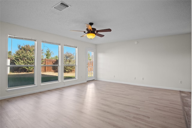 empty room with a textured ceiling, light hardwood / wood-style flooring, and ceiling fan