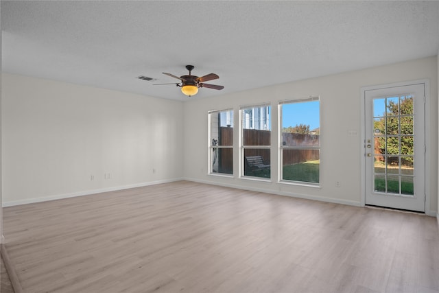 spare room with ceiling fan, a textured ceiling, a healthy amount of sunlight, and light wood-type flooring