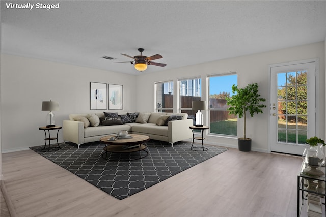 living room featuring ceiling fan, dark wood-type flooring, and a textured ceiling