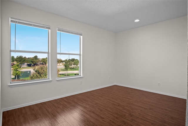 unfurnished room with dark wood finished floors, recessed lighting, a textured ceiling, and baseboards