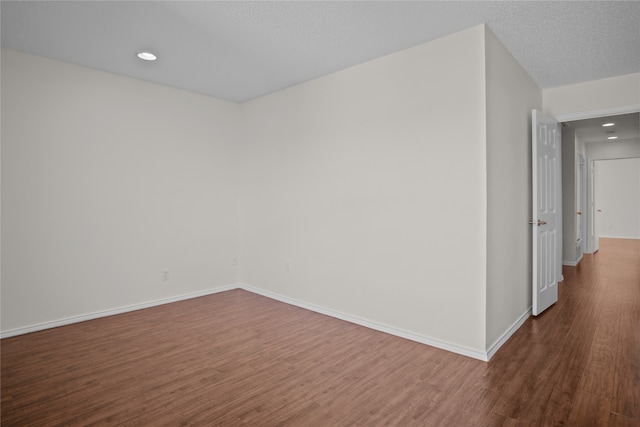 spare room with recessed lighting, baseboards, dark wood-style flooring, and a textured ceiling