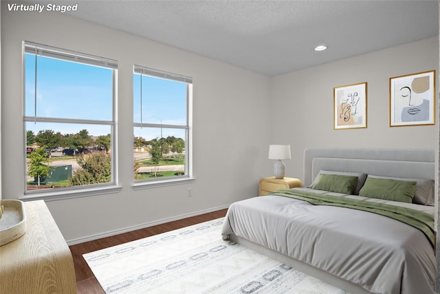 bedroom featuring recessed lighting, baseboards, a textured ceiling, and wood finished floors