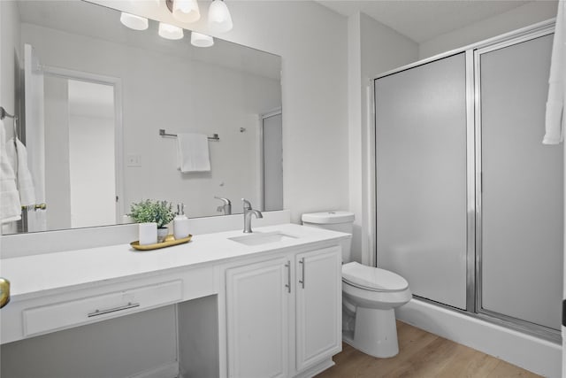 bathroom with hardwood / wood-style flooring, vanity, toilet, and an enclosed shower