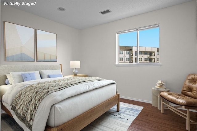 bedroom with visible vents, baseboards, and wood finished floors