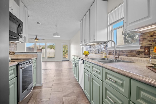 kitchen with appliances with stainless steel finishes, sink, white cabinets, decorative backsplash, and a textured ceiling