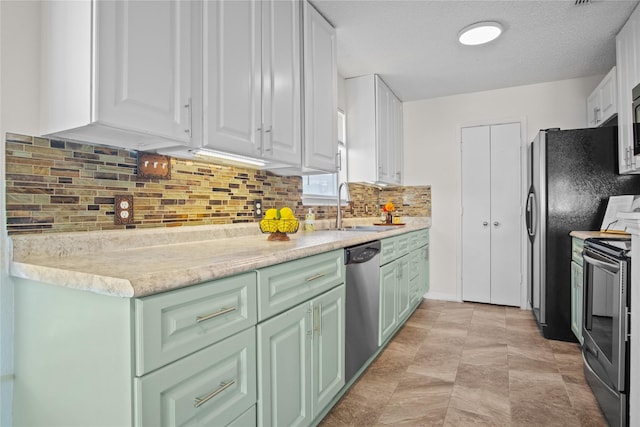 kitchen featuring sink, appliances with stainless steel finishes, white cabinetry, tasteful backsplash, and a textured ceiling