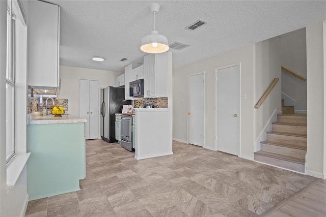 kitchen with visible vents, backsplash, black microwave, light countertops, and white cabinets