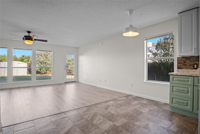 interior space with light wood-type flooring, a wealth of natural light, a textured ceiling, and ceiling fan