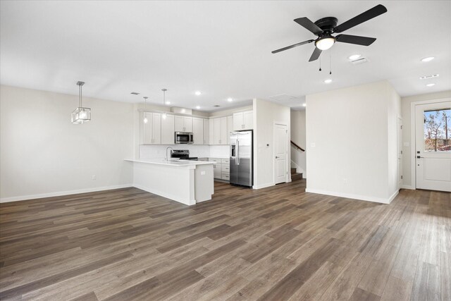 kitchen featuring dark wood-type flooring, white cabinets, hanging light fixtures, kitchen peninsula, and stainless steel appliances