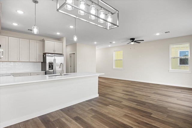 kitchen featuring stainless steel fridge, backsplash, ceiling fan, sink, and pendant lighting