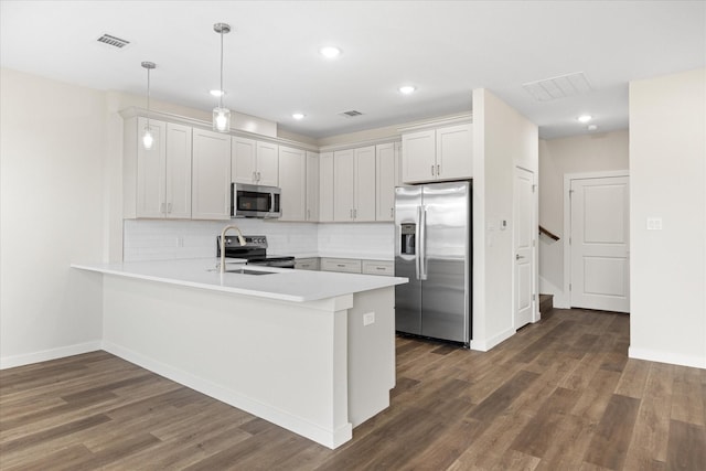 kitchen with kitchen peninsula, decorative light fixtures, dark hardwood / wood-style flooring, white cabinetry, and stainless steel appliances