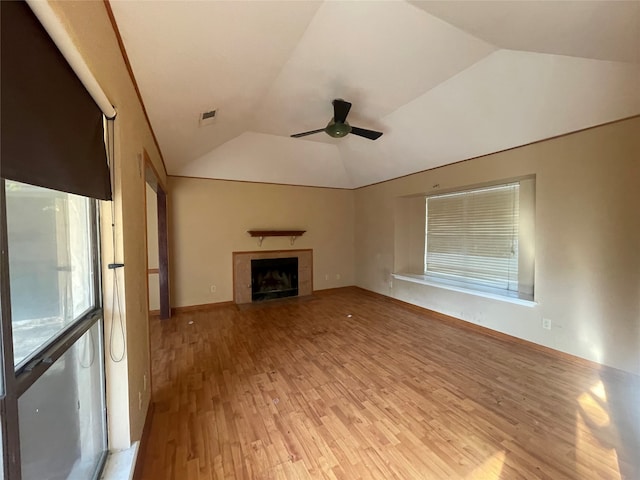 unfurnished living room featuring vaulted ceiling, a tiled fireplace, light hardwood / wood-style floors, and ceiling fan