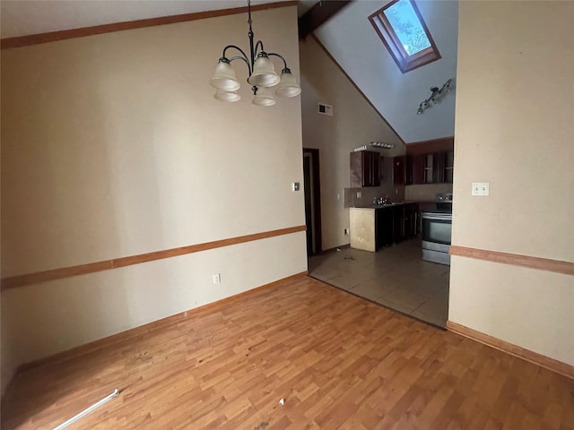 unfurnished living room with sink, a skylight, light hardwood / wood-style floors, a notable chandelier, and high vaulted ceiling