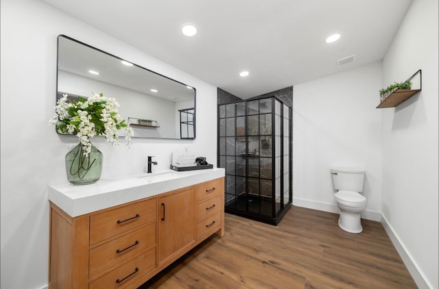 bathroom with hardwood / wood-style flooring, vanity, toilet, and walk in shower