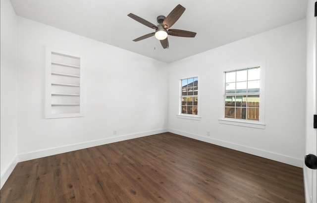 spare room with built in shelves, ceiling fan, and dark hardwood / wood-style flooring