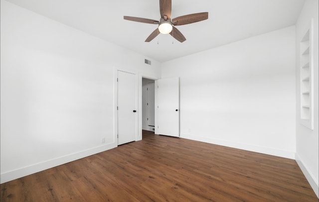 unfurnished room featuring built in shelves, ceiling fan, and dark wood-type flooring