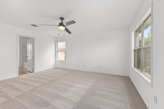 empty room featuring light colored carpet, a wealth of natural light, and ceiling fan