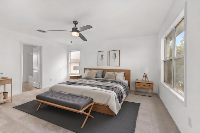 bedroom with light colored carpet, ensuite bath, and ceiling fan