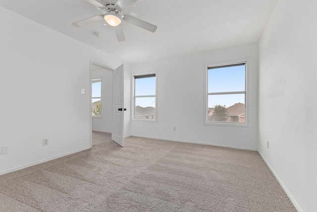 spare room with plenty of natural light, ceiling fan, and light colored carpet