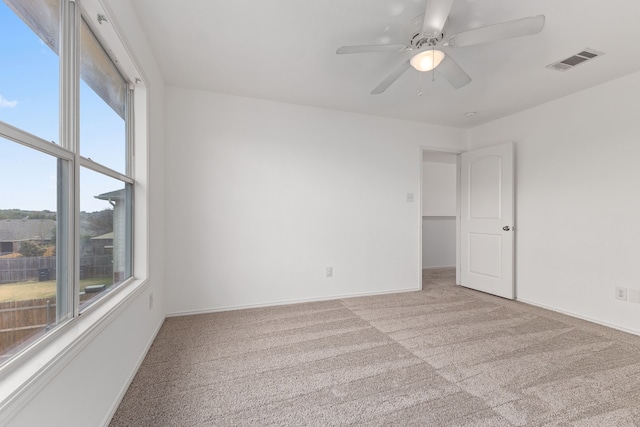 spare room with light carpet, plenty of natural light, and ceiling fan