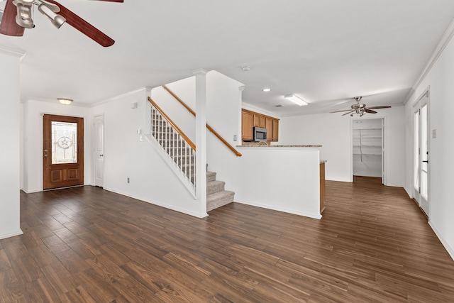 unfurnished living room with a healthy amount of sunlight, crown molding, ceiling fan, and dark wood-type flooring