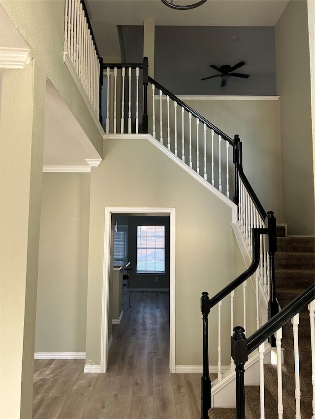 staircase featuring a towering ceiling, crown molding, and wood-type flooring