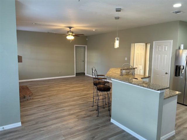 kitchen with stainless steel fridge with ice dispenser, hardwood / wood-style floors, and pendant lighting