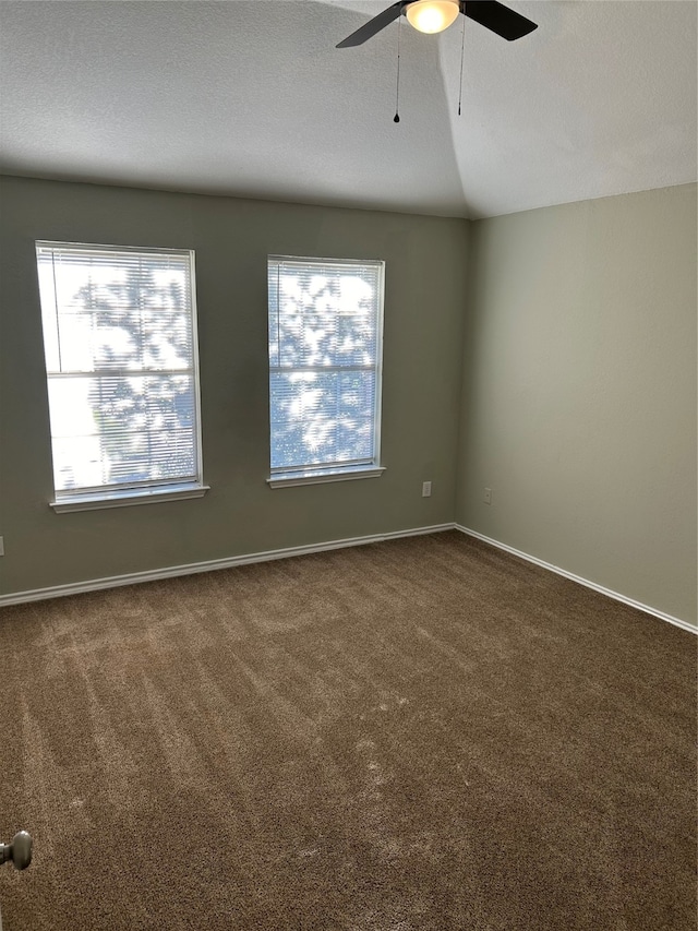 unfurnished room with lofted ceiling, a textured ceiling, ceiling fan, and dark colored carpet