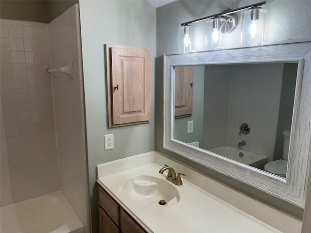 full bathroom featuring tiled shower / bath, vanity, and toilet