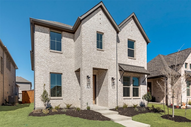 view of front of home with cooling unit, brick siding, fence, and a front lawn