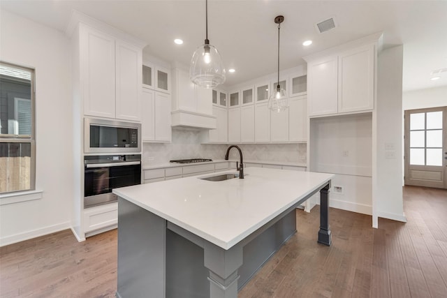 kitchen with stainless steel appliances, visible vents, a sink, and wood finished floors