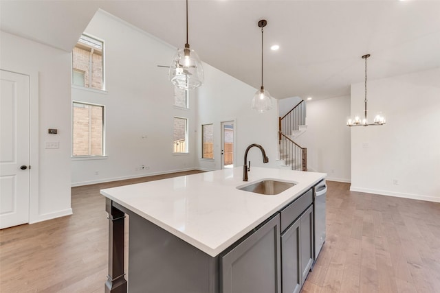 kitchen featuring dishwasher, gray cabinets, a sink, and light wood-style flooring