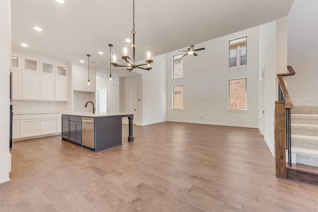 kitchen with a kitchen island with sink, open floor plan, white cabinets, and stainless steel dishwasher