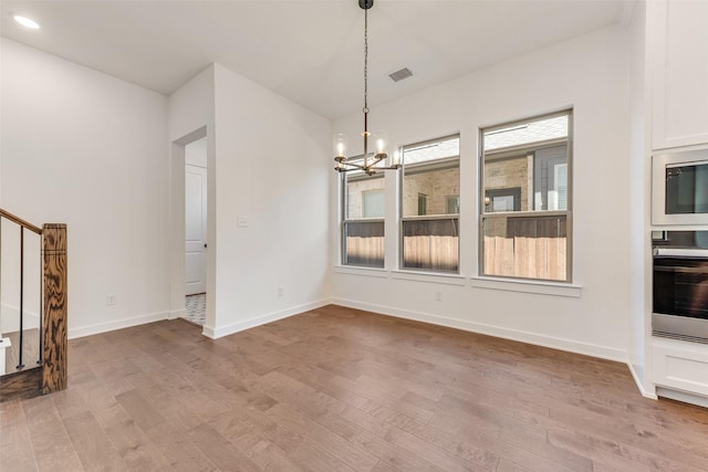 unfurnished dining area with light wood-style flooring, a notable chandelier, visible vents, baseboards, and stairs