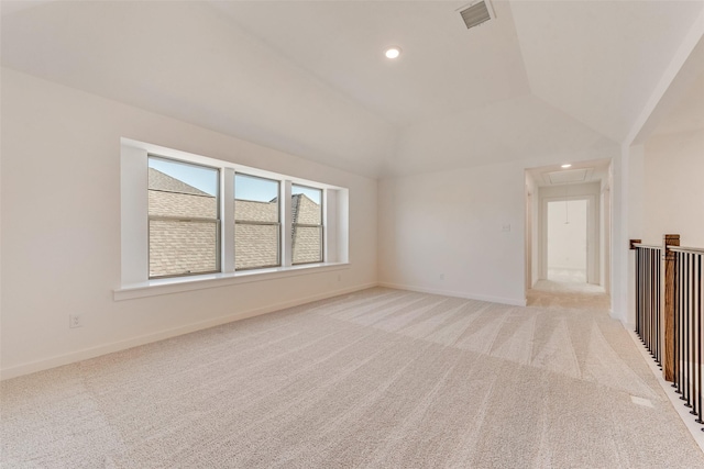 empty room featuring lofted ceiling, light carpet, visible vents, baseboards, and attic access