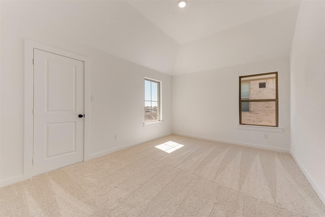 empty room featuring lofted ceiling, baseboards, and carpet flooring