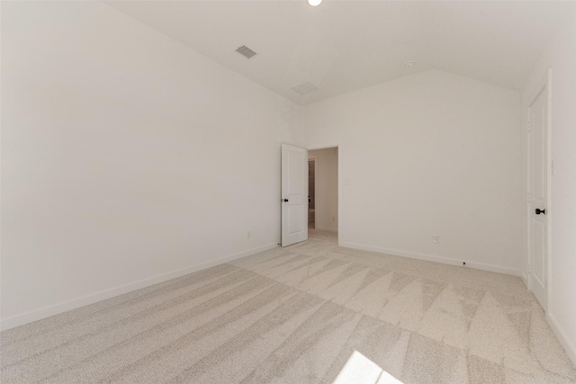 spare room featuring lofted ceiling, baseboards, visible vents, and light colored carpet