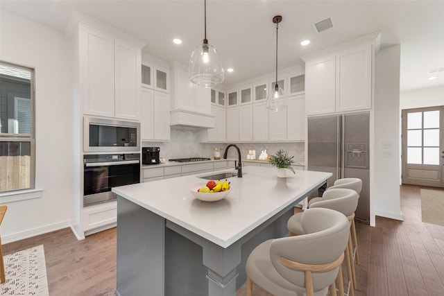 kitchen with visible vents, built in microwave, gas stovetop, stainless steel oven, and a sink