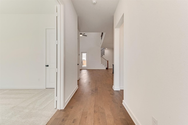 hall with stairs, wood finished floors, and baseboards