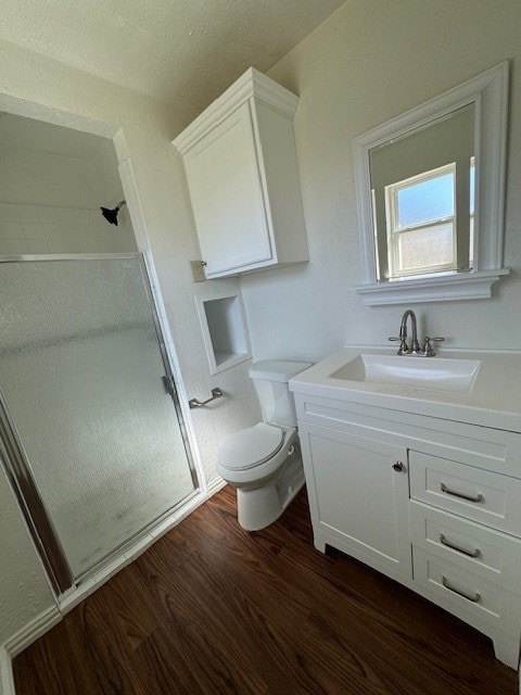 bathroom featuring a shower with door, vanity, wood-type flooring, and toilet